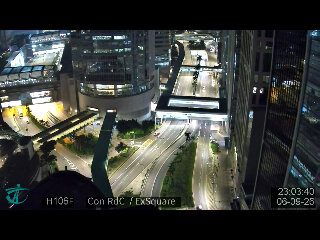 香港中环夜景：人行天桥灯白如练，路口车流亮着红色尾灯，高楼格子间疏疏落灯